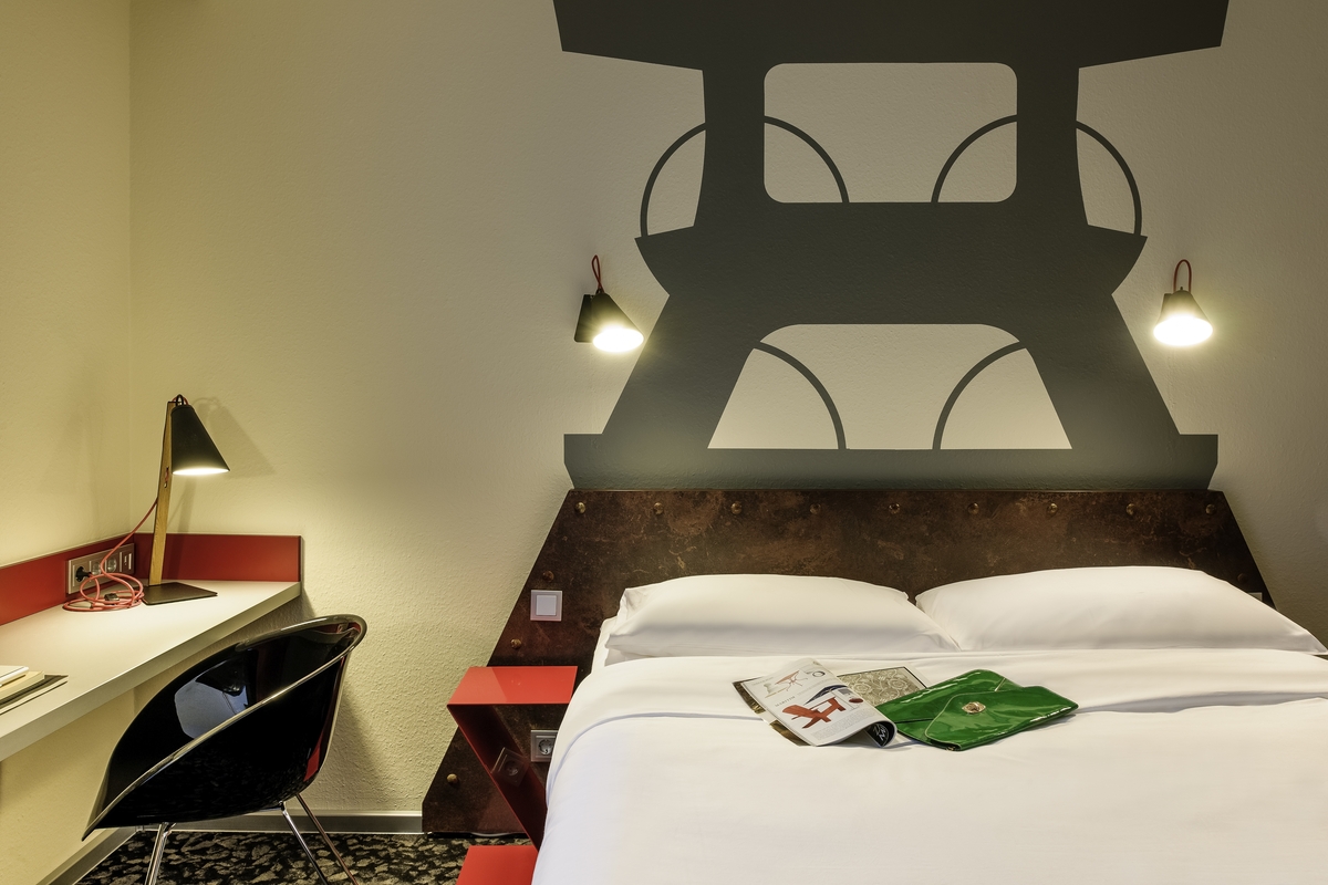 Gemütliches Hotelzimmer: modernes Design, Wanddekoration eines Turms, Schreibtisch, Bett.