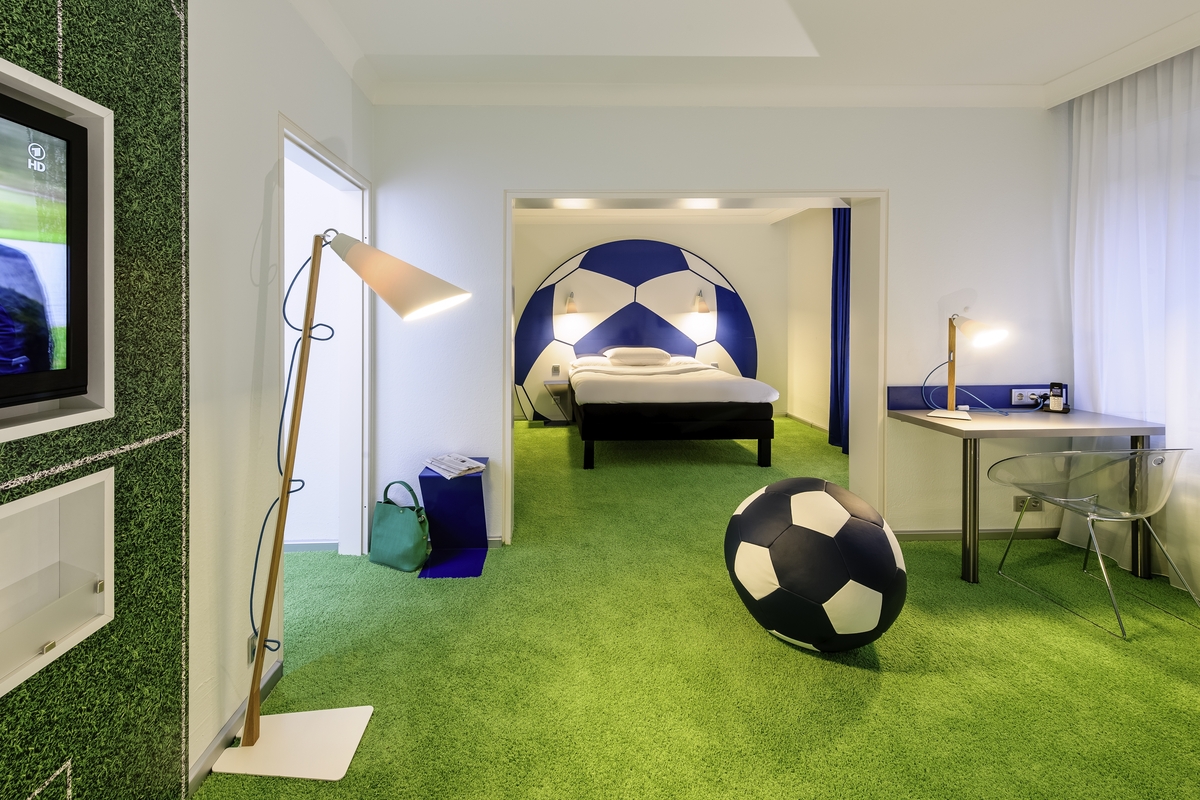 Ein Zimmer mit grünem Teppichboden, großem Fußball-Design und moderner Inneneinrichtung.