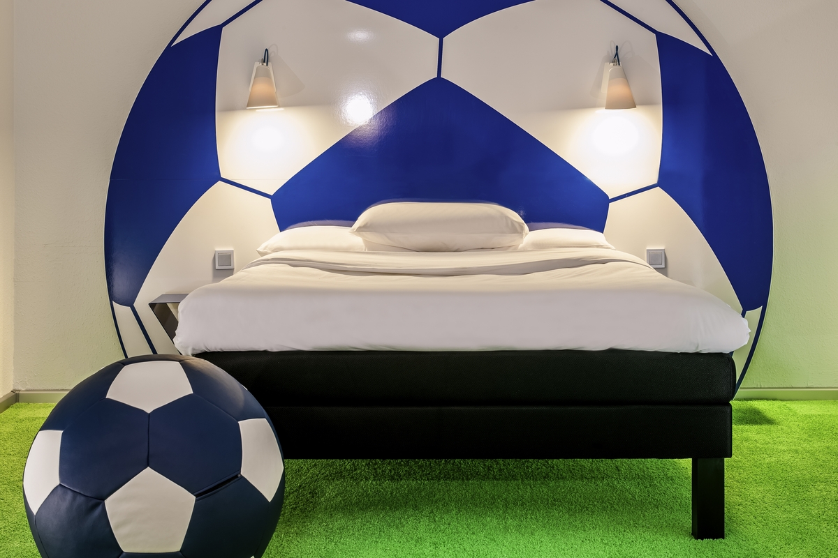 Ein modernes Zimmer mit fußballförmigem Kopfteil und passender blauer Dekoration.