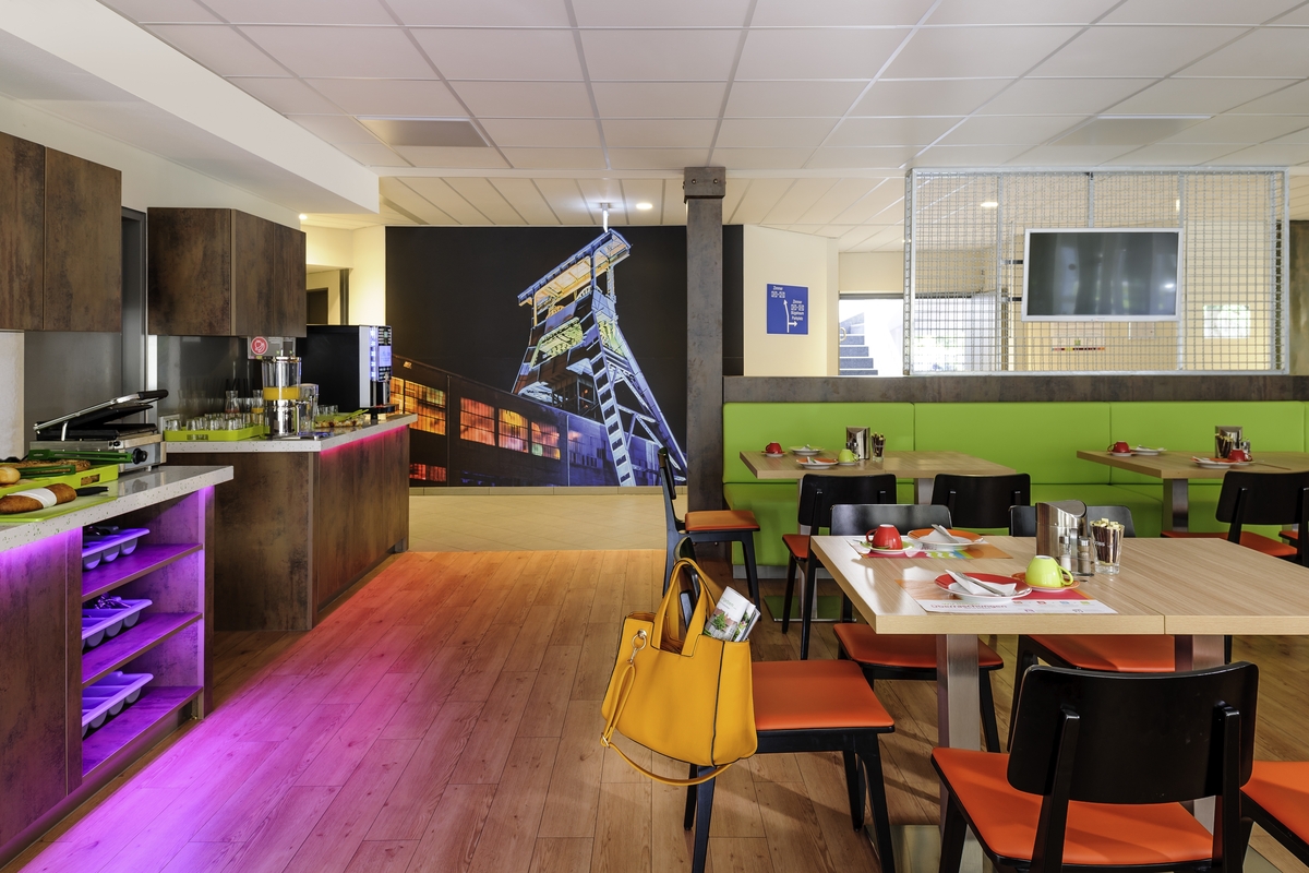 Ein modernes Café mit farbenfrohen Möbeln, einem beleuchteten Tresen und Wandkunst der Industrie.