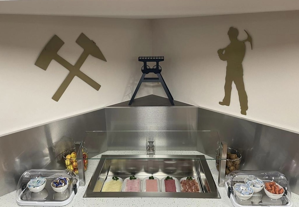 Ausstellung von Bergbauwerkzeugen und -symbolen in einem Raum mit Essen und Dekor.