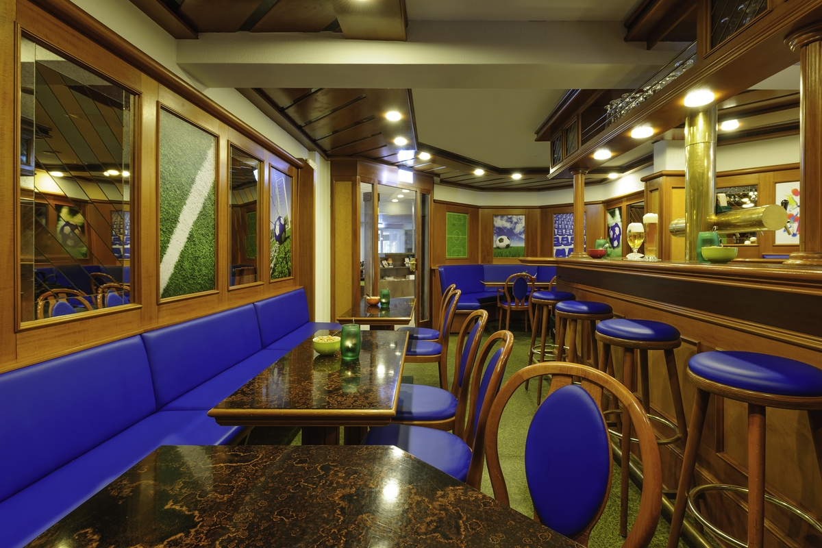Leeres Café mit blauen Sitzpolstern, Holzmöbeln und dekorativen Spiegeln.