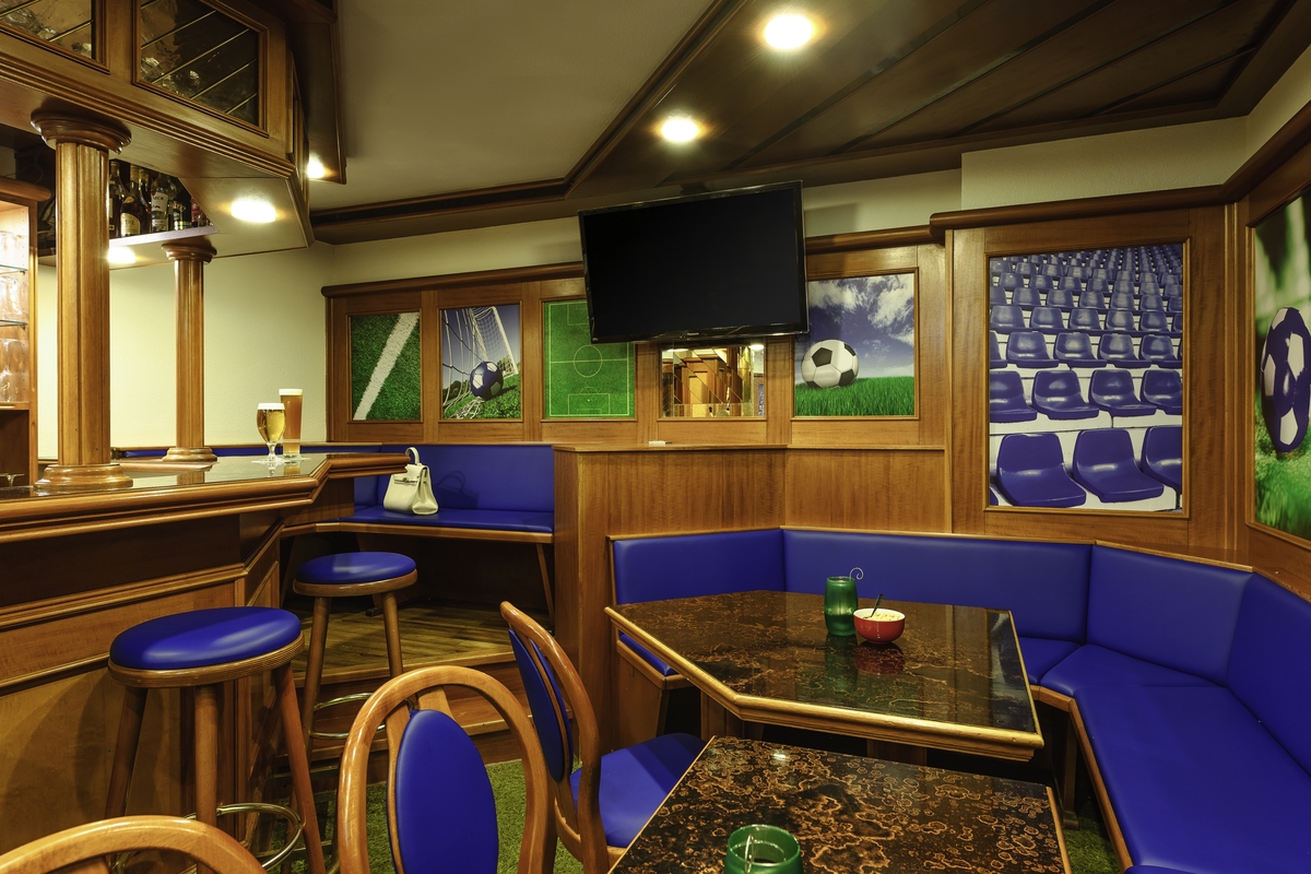 Holzgetäfelte Kneipe mit blauen Sitzpolstern, Frankfurter Fußballthema, Fernseher an der Wand.