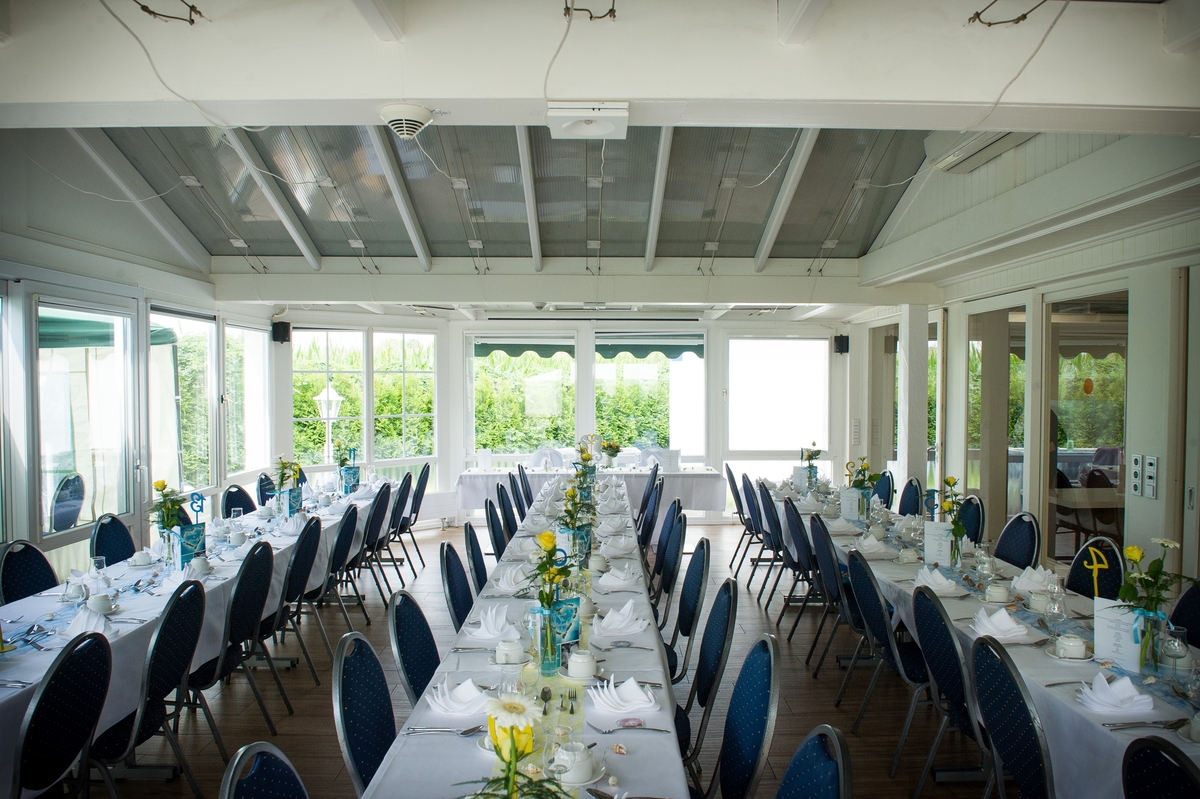 Großer, eleganter Speisesaal mit langen gedeckten Tischen, blauen Stühlen und Blumenarrangements.