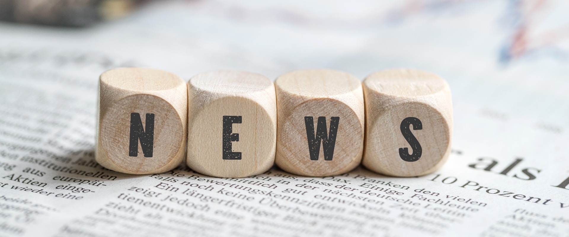 Würfel mit dem Wort "NEWS" auf einer Zeitung